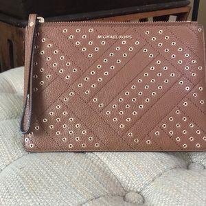 Michael Kors leather wristlet with gold rings adorning the front.